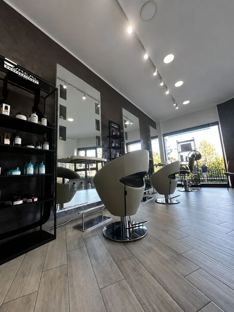 Interno del salone parrucchiera con postazioni di taglio e specchi